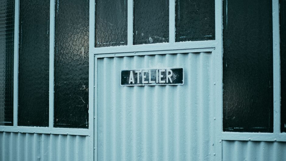 Rustic workshop entrance with 'atelier' sign, showcasing vintage industrial design.